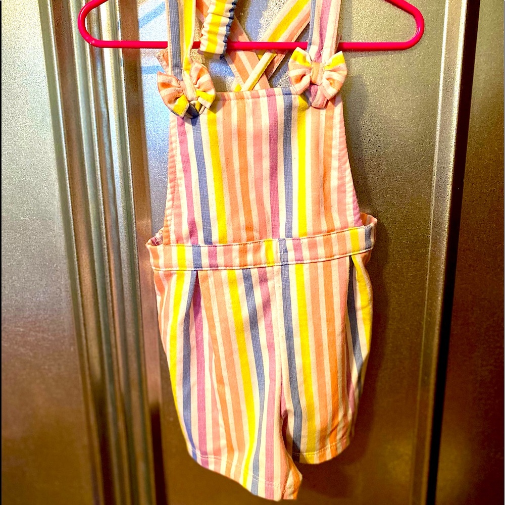 Adorable shorts overalls with matching bow.
